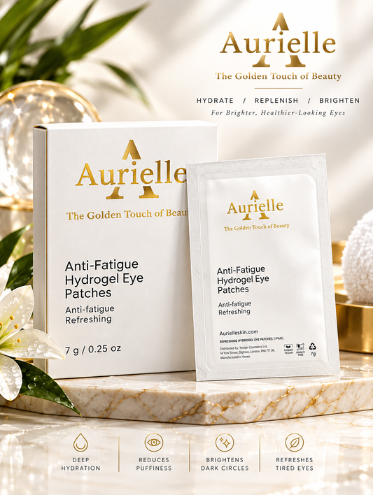 Aurielle Anti-Fatigue Hydrogel Eye Patches shown with their white and gold retail box and a single sachet, styled on a marble surface with decorative flowers and soft lighting.